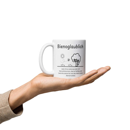 Bienoglaublich Keramiktasse in Weiß - neues Wort für Leichtigkeit und Wachstum - Tasse auf Hand - Frontansicht mit Henkel links - Wortstolz Design