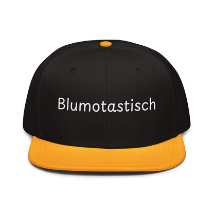 Blumotastisch Snapback Cap in Schwarz - Gold aus Acryl-Woll-Mix - neues Wort für Perfektion und Schönheit - Front - Wortstolz Design