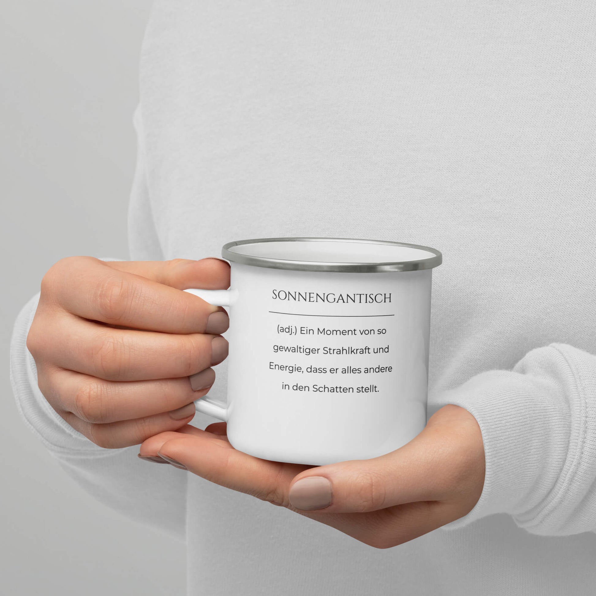 Sonnengantisch Emailletasse in Weiß - neues Wort für Strahlkraft und Energie - Tasse auf Hand - Front mit Henkel links - Wortstolz Design